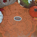A sticker in the shape of a cherry pie sitting on an orange doily with autumn decor in the background.