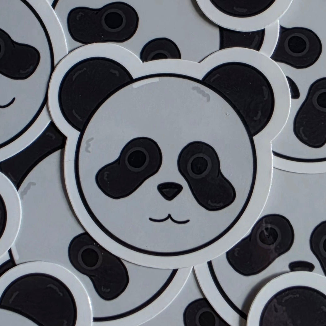 A pile of round white stickers featuring a black and gray panda face design.